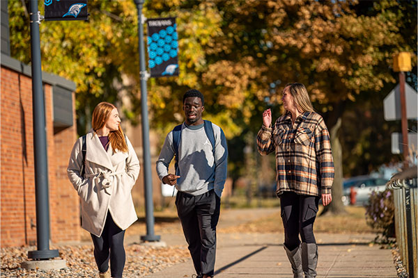 Three people walk along campus.